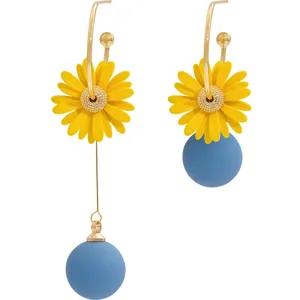 Detailed view of asymmetric daisy earrings with yellow petals and blue matte spheres.