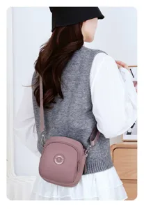 Vista posteriore di una borsa a tracolla in nylon color malva indossata da una modella.