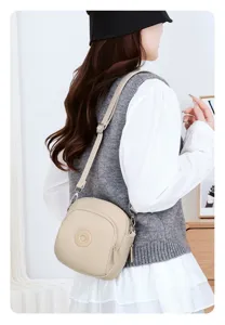 Elegante borsa a tracolla in nylon beige leggero indossata da una modella casual