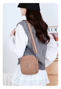 Modella che indossa una leggera borsa a tracolla in nylon beige per il pendolarismo.