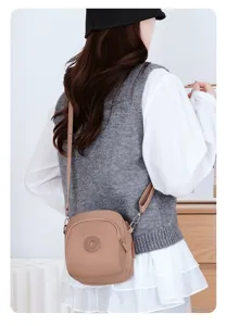 Elegante borsa a tracolla in nylon kaki leggera mostrata su un modello per il pendolarismo