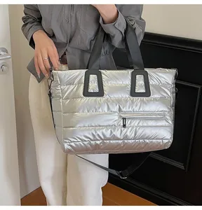 Side view of silver metallic quilted puffer bag showing black handles and pocket