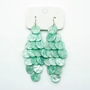 Detail view of mint green pearlescent disc tiered dangling earrings for vacation style.