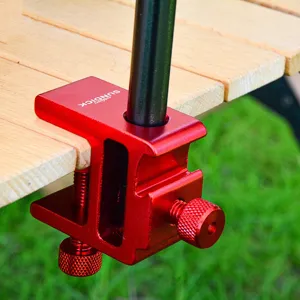 Primer plano del soporte de lámpara de camping de aluminio rojo fijado en mesa de madera.