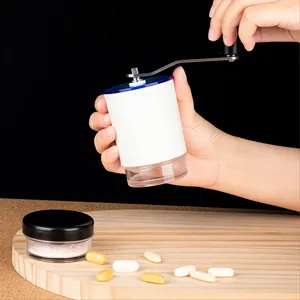 Close-up of manual pill grinder being operated by hand over a wooden board