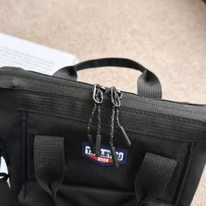 Gedetailleerde close-up van ritsen en merklogo op een zwarte casual crossbodytas