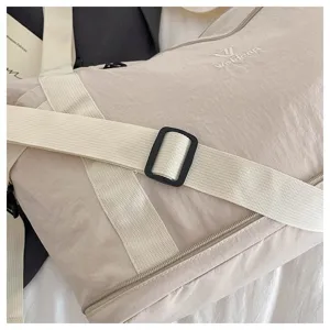 Close-up view of the beige nylon travel duffel bag, showing durable wide strap and buckle.