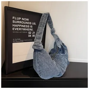Macro view of blue denim hobo bag with unique knotted strap and washed vintage texture.