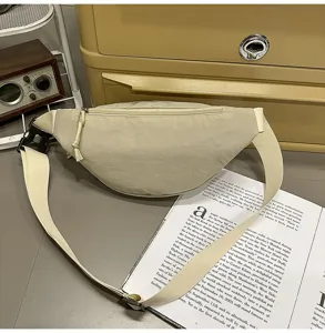 Minimalist beige crossbody waist bag displayed on a vintage desk with a magazine.