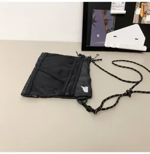 Detail of black nylon tactical crossbody bag with mesh panel and rope strap.