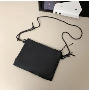 Close-up of black streetwear crossbody bag with patterned paracord strap