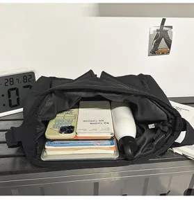 Close-up view of a large black canvas shoulder bag showing spacious interior with books