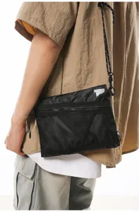 Detail view of Japanese workwear style black mesh crossbody bag worn by a male model