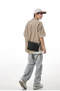 Black Japanese style utility crossbody bag shown on a model in urban outdoor outfit.