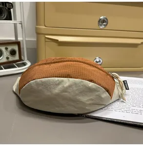 Close-up detail of a two-tone checkered waist bag in orange and cream nylon fabric