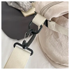 Close-up detail of the durable shoulder strap buckle and zipper on a lightweight travel bag.