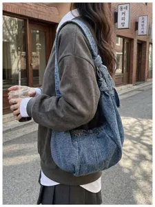Large capacity blue denim shoulder bag in a casual hobo style with knot strap detail.