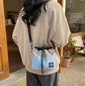 Achteraanzicht van een beige en blauwe nylon emmertas met trekkoord gedragen als crossbodytas