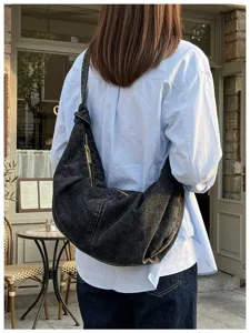Model wearing large capacity black washed denim hobo bag in outdoor cafe setting