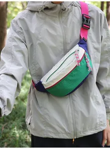 Detailed view of a vibrant multi-color blocking outdoor chest bag worn over a grey jacket