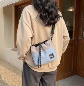 Buitenaanzicht van een persoon met een stijlvolle grijs-blauwe nylon crossbodytas met koord