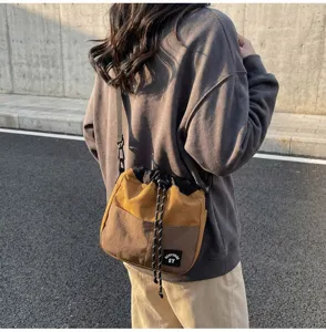 Gedetailleerd overzicht van een nylon crossbody emmertas met koord in bruin en geel
