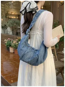 Casual large capacity blue denim hobo shoulder bag worn by model in a garden setting