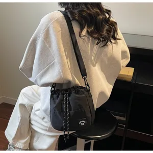 Gedetailleerd overzicht van een casual zwarte nylon bucket bag met trekkoord op een model