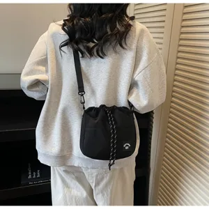 Achteraanzicht van een model met een minimalistische zwarte nylon bucketbag met trekkoord