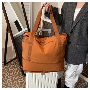 Orange large capacity travel bag detail, showing durable nylon fabric and sturdy handles.