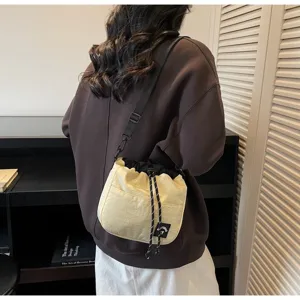 Achteraanzicht van een persoon met een crème nylon crossbody emmertas.