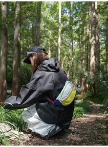 Colorful sports crossbody bag worn outdoors in a forest setting by a female model.