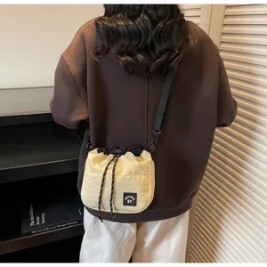 Achteraanzicht van een model met een stijlvolle beige nylon bucketbag met trekkoord