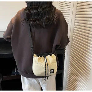 Detailweergave van een casual beige nylon bucketbag met trekkoord crossbody gedragen
