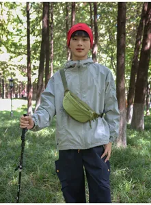 Green corduroy crossbody waist bag shown on model in an outdoor forest setting.