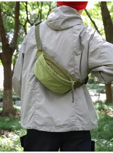 Outdoor olive green crossbody fanny pack worn by a person in a natural forest setting