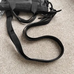 Detail van de verstelbare zwarte nylon schouderriem op een modieuze casual crossbodytas