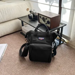 Zwarte getextureerde crossbodytas met vintage camera- en radio-accessoires.