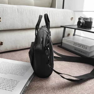 Zijprofiel detail van een zwarte nylon crossbody tas in een moderne lifestyle setting