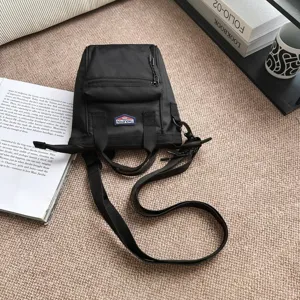 Detailopname van de zwarte multifunctionele nylon crossbodytas van hoogwaardige stof