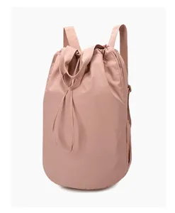 Side-front view of a stylish dusty rose pink nylon drawstring backpack with dual straps