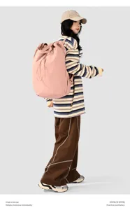 Lifestyle detail of the lightweight pink large-capacity nylon backpack worn by a model.