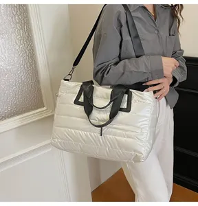 Close-up of a stylish white quilted puffer tote bag worn by a model in casual setting