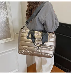 Close-up detail of a large metallic gold quilted puffer tote bag worn by a model