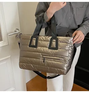 Large metallic puffer quilted tote bag held by a model in casual indoor setting