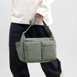 Detailed side view of a sage green multi-pocket nylon messenger bag in Japanese workwear style