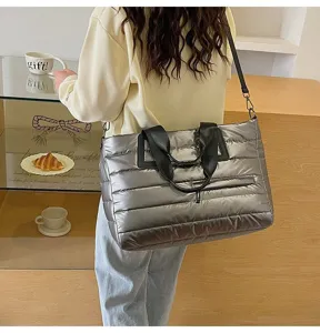 Lifestyle detail of a large silver metallic puffer tote bag worn by a model