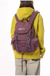 Rückansicht eines lila Wanderrucksacks, getragen von einem Model in gelber Jacke.
