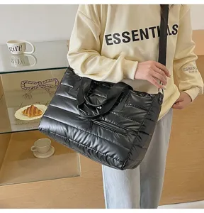 Black quilted puffer tote bag shown on model highlighting its large size and style