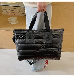 Macro view of black puffer tote bag highlighting quilted texture and handle attachment.